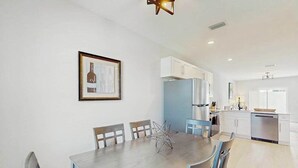 A modern kitchen with white cabinets, a dining table with chairs, and a framed picture on the wall. - Dog friendly duplex with hot tub, internet, and washer and dryer (Englewood)