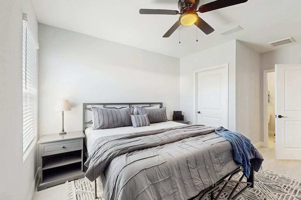 Une chambre à coucher avec un lit, une table de chevet et un ventilateur de plafond.