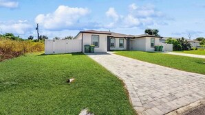 A two-story residential building with a paved driveway and a well-maintained lawn. - Dog friendly duplex with hot tub, internet, and washer and dryer (Englewood)