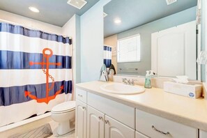 A bathroom with a striped shower curtain, a sink, a mirror, and a toilet. - Luxe waterfront townhome with water views, 4 decks, & all-new interior (Englewood)