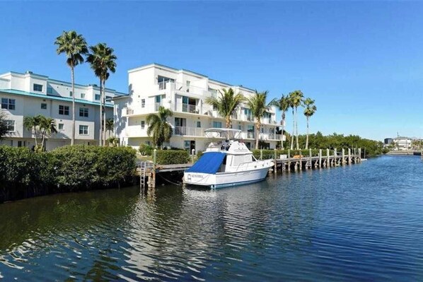 A waterfront hotel with a boat dock, palm trees, and a clear blue sky. - Luxe waterfront townhome with water views, 4 decks, & all-new interior (Englewood)
