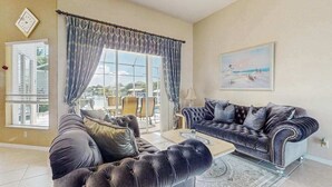 Ein Wohnzimmer mit großem Fenster, einer Couch, einem Couchtisch und einem Gemälde an der Wand.