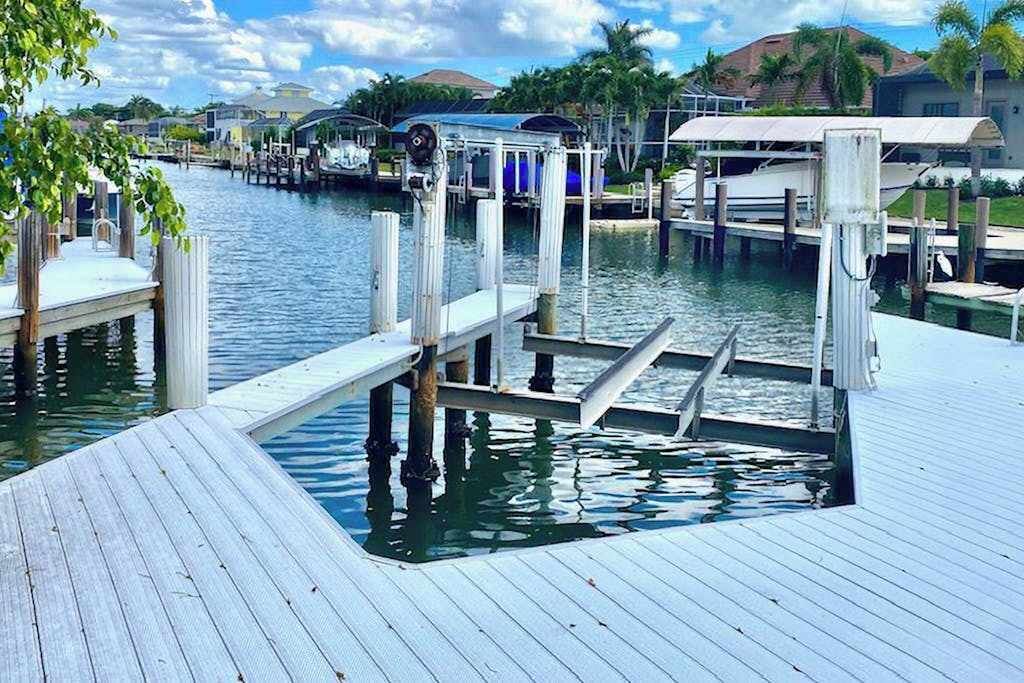 A dock with a boat, a pier, and a house in the background.