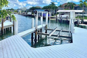 A dock with a boat, a pier, and a house in the background. - Dog friendly home with private pool, washer & dryer, and Wifi (Marco Island)