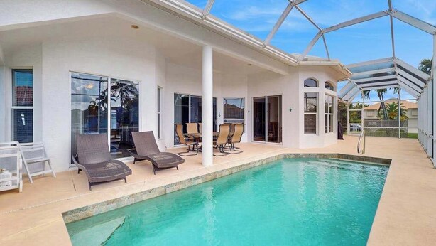 Ein Poolbereich mit Liegestühlen, einem Tisch und einer überdachten Terrasse.