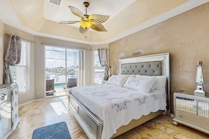 A bedroom with a bed, a ceiling fan, a nightstand, and a view through the window. - Dog friendly home with private pool, washer & dryer, and Wifi (Marco Island)