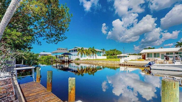 A marina with docked boats, a wooden dock, and a clear blue sky. - Elegant dog-friendly all-suite boater’s paradise near beach with private dock (Naples)