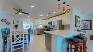 A modern kitchen with a central island, bar stools, and pendant lighting. - Elegant dog-friendly all-suite boater’s paradise near beach with private dock (Naples)