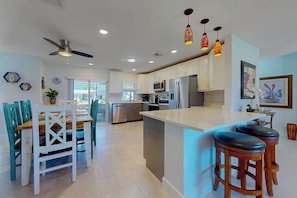 Una cocina moderna con una isla central, taburetes de bar e iluminación colgante.
