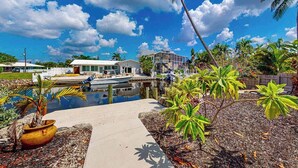 A waterfront property with a pool, palm trees, and a house. - Elegant dog-friendly all-suite boater’s paradise near beach with private dock (Naples)