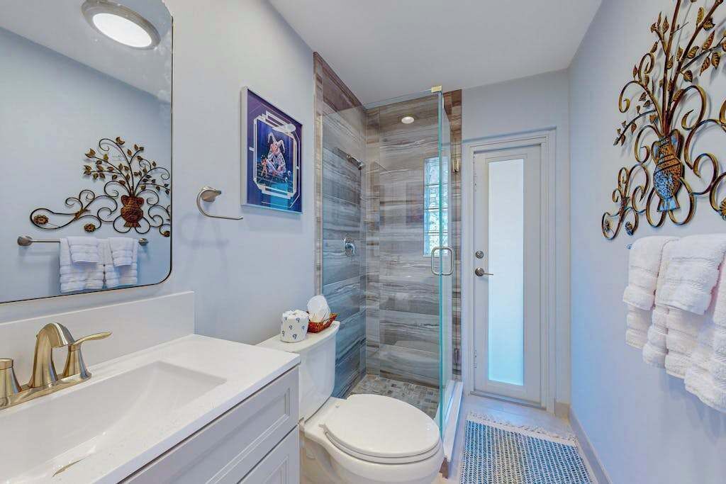 Un baño con cabina de ducha de vidrio, un lavamanos blanco y un inodoro.