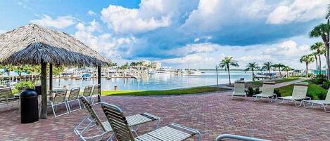 A waterfront resort with lounge chairs, a thatched umbrella, and a marina.