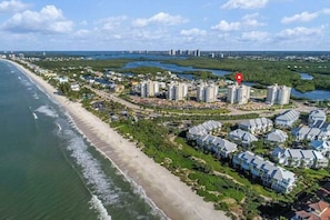An aerial view of a coastal residential area with beachfront properties, a marina, and a dense cluster of high-rise buildings in the background. - Great location, stunning views, near beach - great for snowbirds (Bonita Springs)