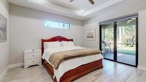 A bedroom with a bed, a nightstand, a ceiling fan, a window, and a sliding glass door leading to an outdoor area. - Luxurious home with private washer/dryer, enclosed yard, WiFi, & screened lanai (Bonita Springs)