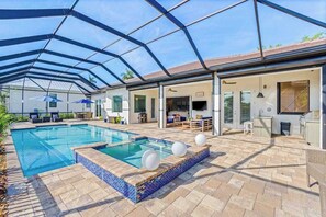 A covered outdoor swimming pool with a patio area, a kitchen, and a dining space. - Luxe, waterfront home with pool, spa, dock & gorgeous backyard (Bonita Springs)
