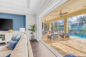 A living room with a TV, sofa, and potted plants. - Luxe, waterfront home with pool, spa, dock & gorgeous backyard (Bonita Springs)