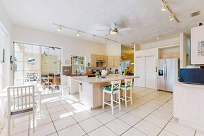 Eine geräumige Küche mit einer zentralen Kochinsel, Deckenventilator und Kühlschrank.