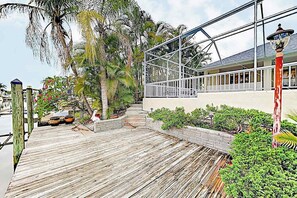 Eine Holzterrasse mit Geländer, ein Gebäude mit Balkon und eine Straßenlaterne.