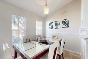 A dining area with a glass table, white chairs, and a chandelier. - Surfside oasis, dog friendly, snow-bird friendly with pool (Cape Coral)