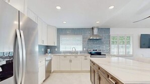Una cocina moderna con una isla grande, electrodomésticos de acero inoxidable y un salpicadero azul.