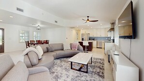 Una sala moderna con un sofá modular, una mesa de centro y un comedor con sillas.