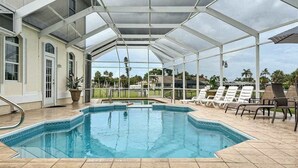 A covered swimming pool with lounge chairs and a view of the surrounding landscape. - Villa Euphoria: Chic 2-unit, canal-front retreat with 2 pools & private dock (Cape Coral)