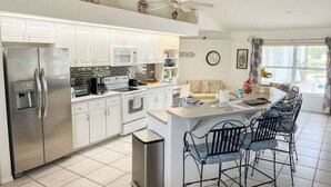 A modern kitchen with white cabinets, stainless steel appliances, and a central island with bar stools. - Villa Euphoria: Chic 2-unit, canal-front retreat with 2 pools & private dock (Cape Coral)