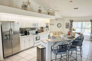 A modern kitchen with white cabinets, stainless steel appliances, and a central island with bar stools. - Villa Euphoria: Chic 2-unit, canal-front retreat with 2 pools & private dock (Cape Coral)