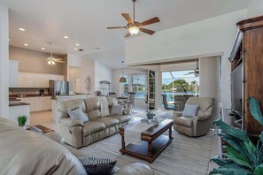 A spacious living area with a sofa set, a coffee table, and a ceiling fan. - Updated lake-view luxury home with private heated pool & jetted tub (Cape Coral)