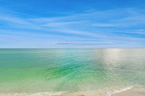 Ein Strand mit klarem türkisblauem Wasser und blauem Himmel.