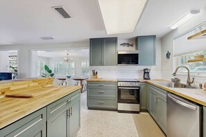 Eine moderne Küche mit grauen Schränken, Edelstahlgeräten und einer Holz Arbeitsplatte.