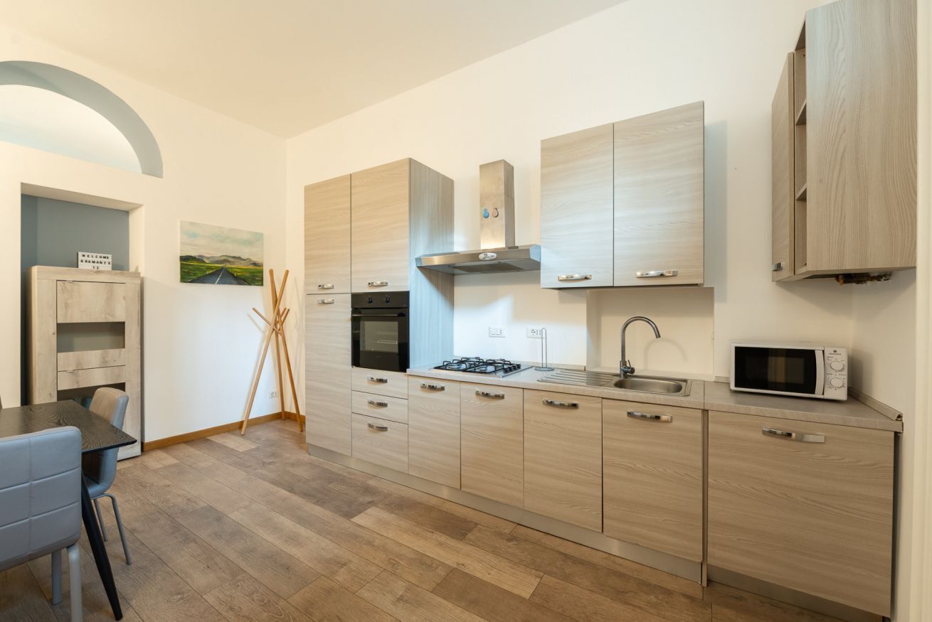 Eine moderne Küche mit hellen Holzschränken, einem Gasherd, einer Mikrowelle und einem Backofen.