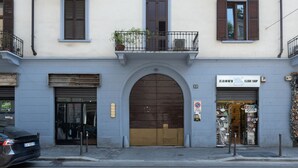 Um edifício com uma grande entrada em arco, uma loja à direita e um carro estacionado na frente.