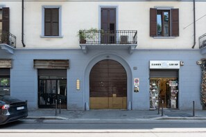 Ein Gebäude mit einem großen Bogenportal, einem Geschäft auf der rechten Seite und einem geparkten Auto davor.