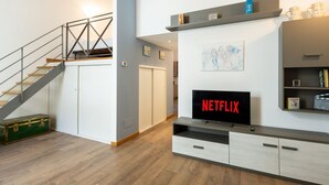 Uma sala de estar moderna com escada, televisão de tela plana e estante.