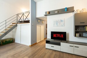 Ein modernes Wohnzimmer mit Treppe, Flachbildfernseher und Bücherregal.