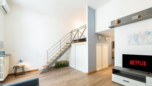 Uma sala de estar moderna com escada, televisão e prateleira fixada na parede.