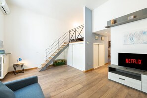 Ein modernes Wohnzimmer mit Treppe, Fernseher und Wandregal.