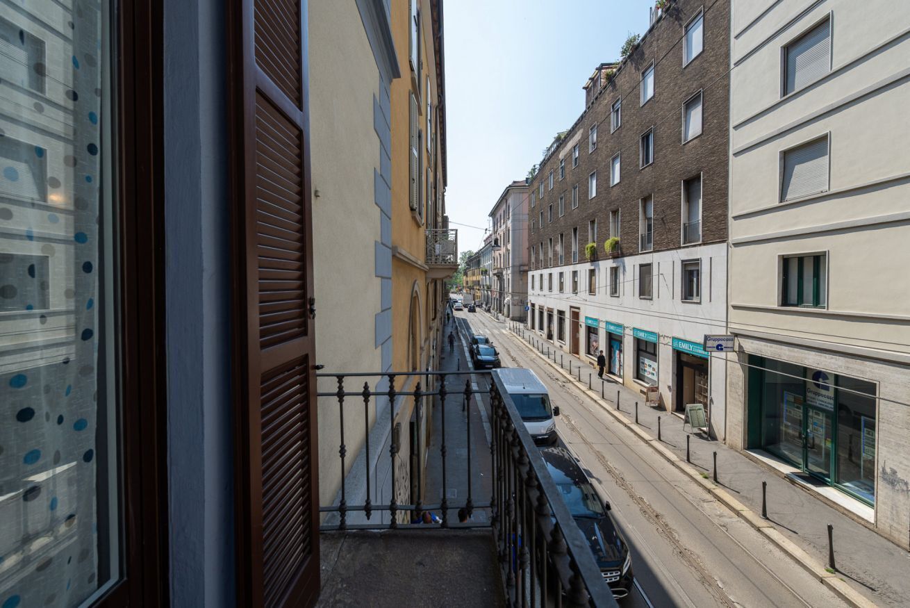 Een smalle straat met gebouwen aan beide zijden, een tram en een voetpad.