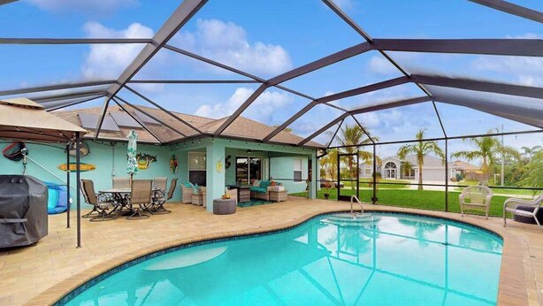 Une piscine avec un patio couvert, du mobilier d’extérieur et une vue sur le paysage environnant.