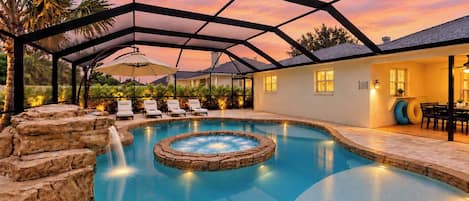 Une piscine avec un jacuzzi, entourée de chaises longues et d’un patio couvert.