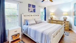 Un dormitorio con cama, mesita de noche, cómoda, ventilador de techo y decoración de estrella de mar.