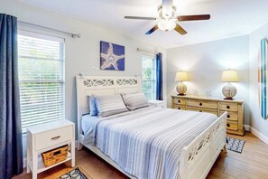 A bedroom with a bed, a nightstand, a dresser, a ceiling fan, and a starfish decoration. - Chic pool home w/ designer, heated, saltwater pool,attached spa, covered patio (Cape Coral)