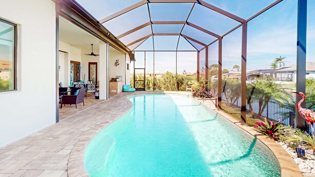 Une piscine entourée de parois en verre, un espace patio aménagé avec des sièges et une vue sur le paysage environnant.