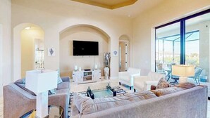 Un salon spacieux doté d’une grande télévision, de sièges confortables et offrant une vue dégagée grâce à de larges fenêtres.