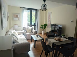 Un soggiorno con divano, tavolino, televisore e tavolo da pranzo con sedie.