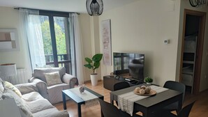 Ein Wohnzimmer mit einer Couch, einem Couchtisch, einem Fernseher und einem Essbereich mit Stühlen und einem Tisch.