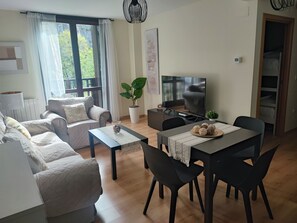 Una sala de estar con sofá, mesa de centro, televisor y un comedor con sillas y mesa.