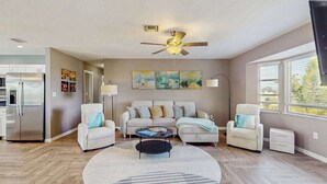 A modern living room with a sofa set, a coffee table, a ceiling fan, and a large window. - Dog friendly house with private pool, lanai, and washer & dryer (Rotonda West)