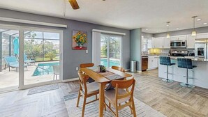A modern kitchen with a dining area, large windows, and a ceiling fan. - Dog friendly house with private pool, lanai, and washer & dryer (Rotonda West)